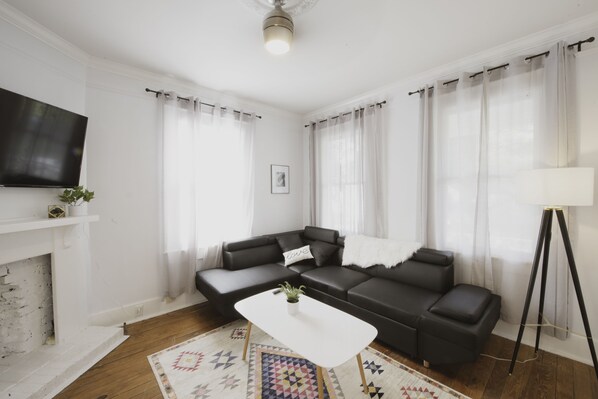 The living room has a sectional sofa and smart TV.