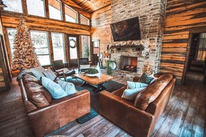 A warm and inviting living space featuring a stone fireplace, rustic wood accents, and plush seating—ideal for family gatherings and cozy nights in.