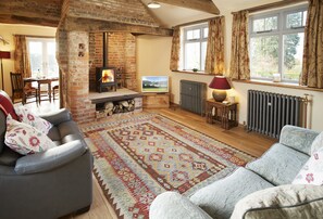 Forge Croft, Yorkshire: Sitting room with comfortable sofas, television and wood burning stove set in the original blacksmith's forge