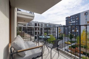 A modern balcony with a comfortable seating area, overlooking a contemporary residential complex.
