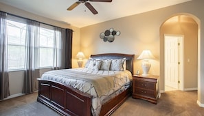 Cozy bedroom with a plush queen bed, ceiling fan, and plenty of natural light for a restful stay.