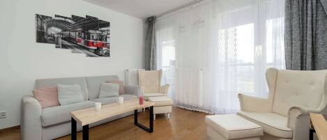 A cozy living space with a soft sofa and large glass doors leading to a terrace, letting in plenty of natural light.
