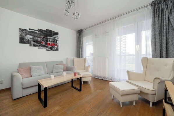 A cozy living space with a soft sofa and large glass doors leading to a terrace, letting in plenty of natural light.