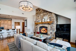 Living room with front door and kitchen in the background. Flatscreen TV.