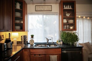 Kitchen sink looks into the large backyard. Well stocked with dishes & cookware.