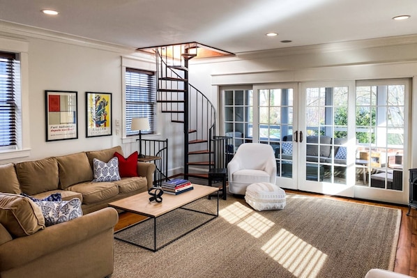 Comfortable furniture in the family room and a spiral staircase goes down to 1st floor bedroom/bath/laundry room.