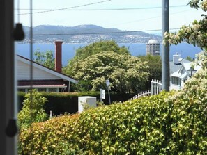 The house is in an elevated position that provides views down to the Derwent River and surrounding tree-lined streets of Sandy Bay.