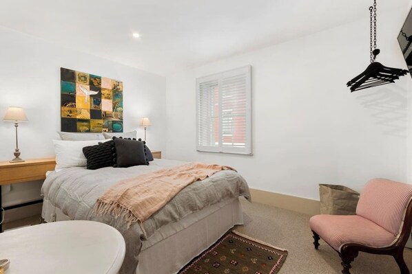 The charming bedroom offers a comfortable queen bed with side tables and reading lights. 