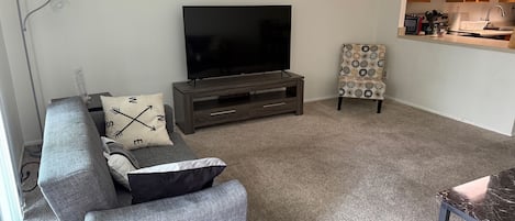 The living room comes furnished with essential pieces, including a comfortable sofa, a coffee table, and a TV stand, providing immediate comfort upon move-in.