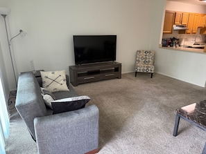 The living room comes furnished with essential pieces, including a comfortable sofa, a coffee table, and a TV stand, providing immediate comfort upon move-in.