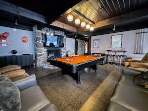 Entertainment space with a pool table, large TV, and direct outdoor access.