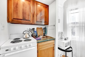 Full electric stove and oven, fully stocked kitchen with all cooking amenities.