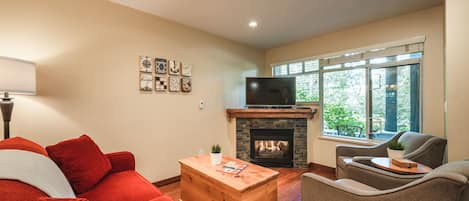 Living Room - Cozy fireplace, SmartTV, large window onto patio, comfortable sofa and lounge chairs.