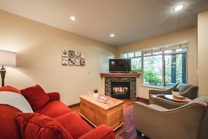 Living Room - Cozy fireplace, SmartTV, large window onto patio, comfortable sofa and lounge chairs.