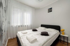Cozy bedroom with natural light and minimalist decor – Comfortable double bed, ideal for rest and relaxation.
