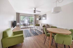 Spacious living room with a cosy sofa, flat-screen TV, and dining area, ideal for entertaining or relaxing.