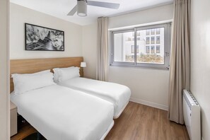 A cosy guest bedroom with two single beds, perfect for friends or family, offering ample natural light and a peaceful ambience.
