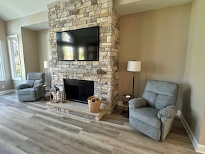 Stone fireplace with flush mount 65" TV and twin recliners