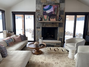 Open floor plan with large stone fireplace and screened sliding doors to patio