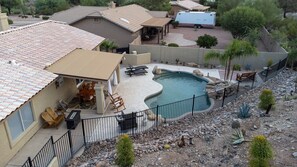Enclosed pool with landscaping above gated area, propane grill & firepit