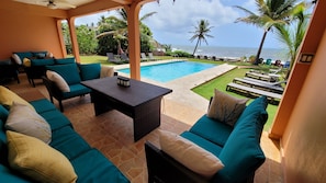 Patio with seating and dining overlooking infinity pool and ocean