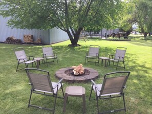 A cozy backyard firepit area with six inviting chairs arranged in a perfect circle, ready for laughter and late-night conversations