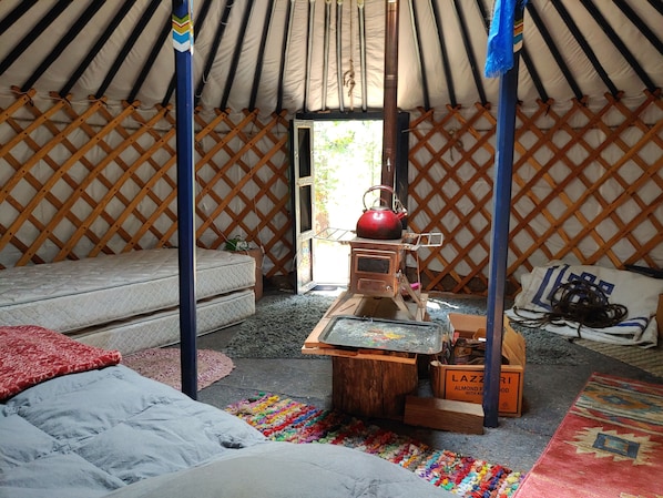 Interior view of yurt shows camping stove and beds.