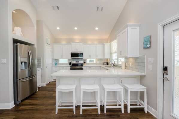 Kitchen with bar seating for 4 and built-in trash bins for convenience.