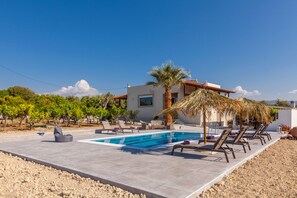 Swimming pool with sunbeds and natural umbrellas