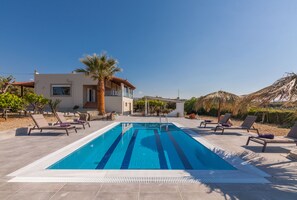 Swimming pool with sunbeds and natural umbrellas