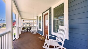 Spacious wrap-around porch features classic rocking chairs and 2 table sets.