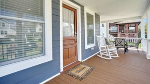 Spacious wrap-around porch features classic rocking chairs and 2 table sets.