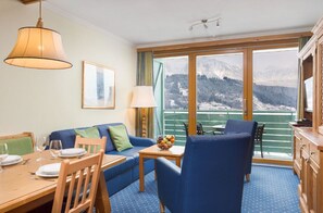 Bright living area with a comfy sofa and access to a balcony offering beautiful mountain views.