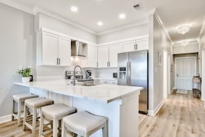 Kitchen has large farmhouse sink and breakfast bar with 4 barstools