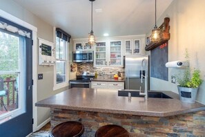This adorable kitchen and breakfast bar feature a refrigerator, oven, microwave and small dishwasher.