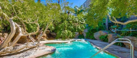 The hut tub is nestled into tropical foliage.