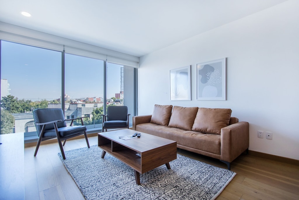 VRBO Mexico City: Apartment with a sofa, two chairs, coffee table and large windows overlooking the city