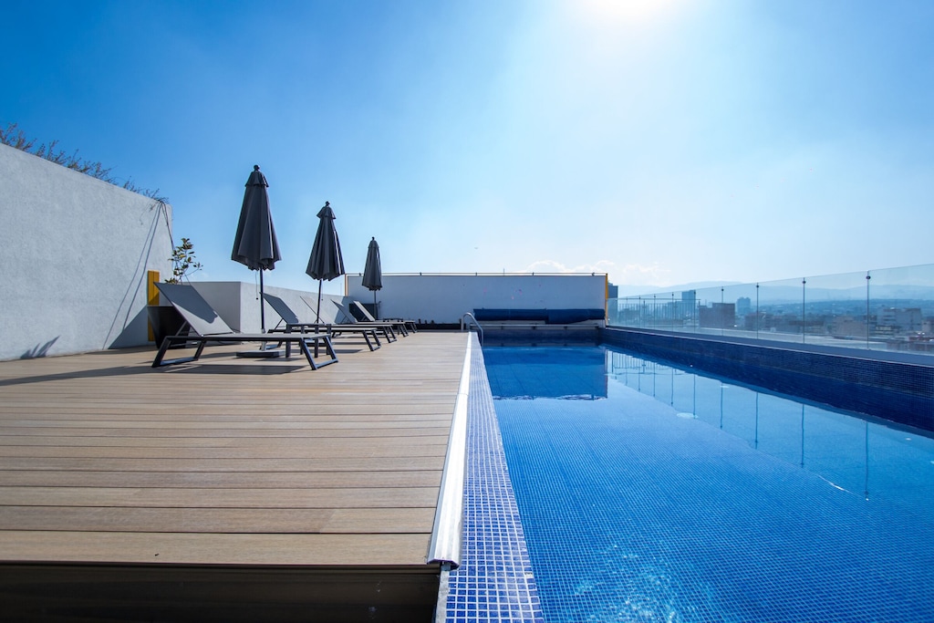 best airbnb mexico city condesa and roma norte | Rooftop pool and lounge deck with chairs and umbrellas overlooking the city