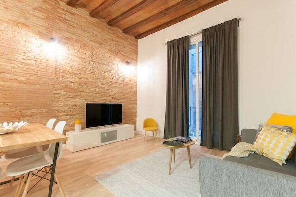 Living room, with big windows, sofa, tv, and french balcony 