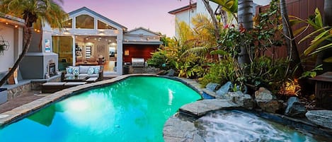 Unwind in your own private oasis featuring a heated pool with a soothing waterfall, a hot tub, and an outdoor lounge complete with a BBQ and fireplace. It's the perfect spot to escape the hustle and bustle