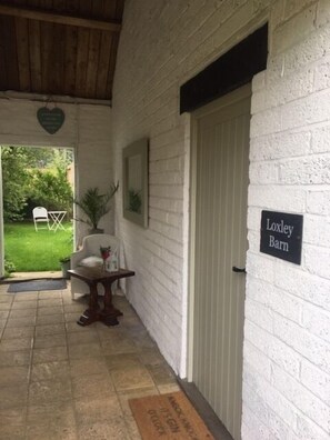 Beautiful porch with chair and table, area for wellington boots leading to own garden area. 