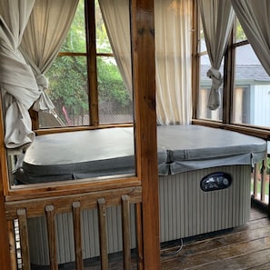 Four man hot tub in large screened in porch off the back of house