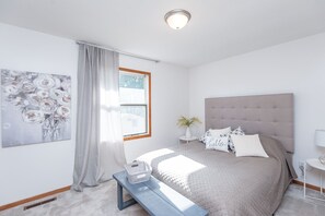 Queen upper bedroom with nighstand tables, lamp, fan dresser and extra bedding.