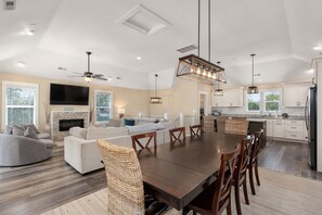 Dining table with a chic lamp, adjoining the living room with a smart TV.