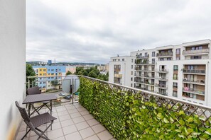 Large balcony with greenery and a view of the city, perfect for morning coffee.