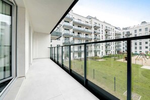 A spacious balcony with a view of a marina, with boats docked on the water, and modern buildings in the background.