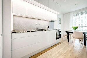 A modern kitchen with white cabinetry, an oven, and a spacious layout that opens to the dining area