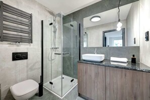 A bathroom with a glass shower, a dark wood vanity, and a sleek design, giving a clean, modern look.