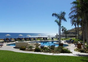 Pool area overlooking the ocean. The pool has 3 hot tubs, seating and umbrellas and beach access.