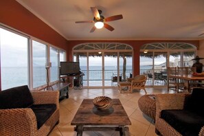 Living room seating area with surrounding windows and views of the ocean.